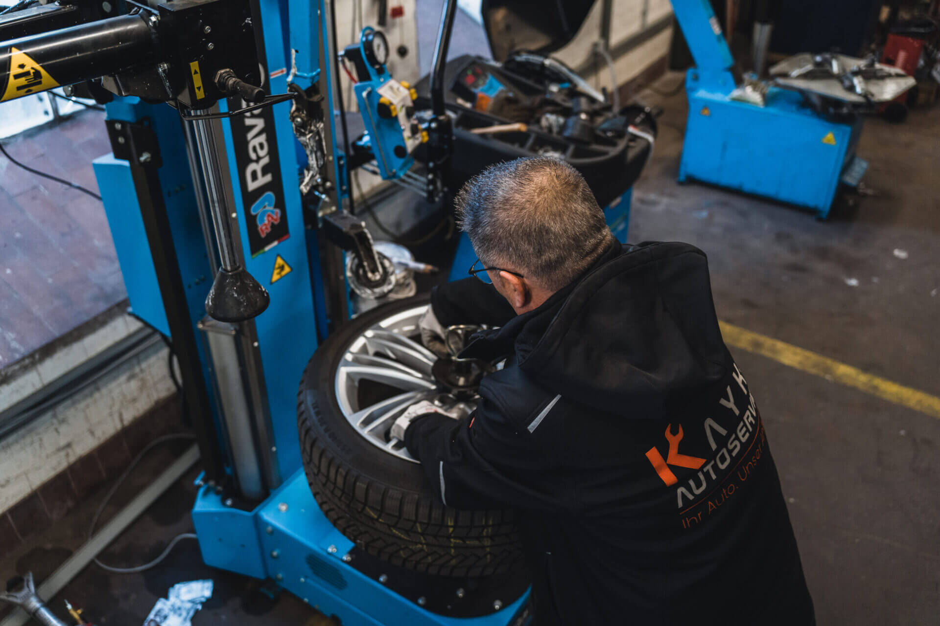 Mechaniker von Kayki Autoservice montiert einen Reifen auf eine Felge mit einer Reifenmontiermaschine in einer Werkstatt in Hildesheim.